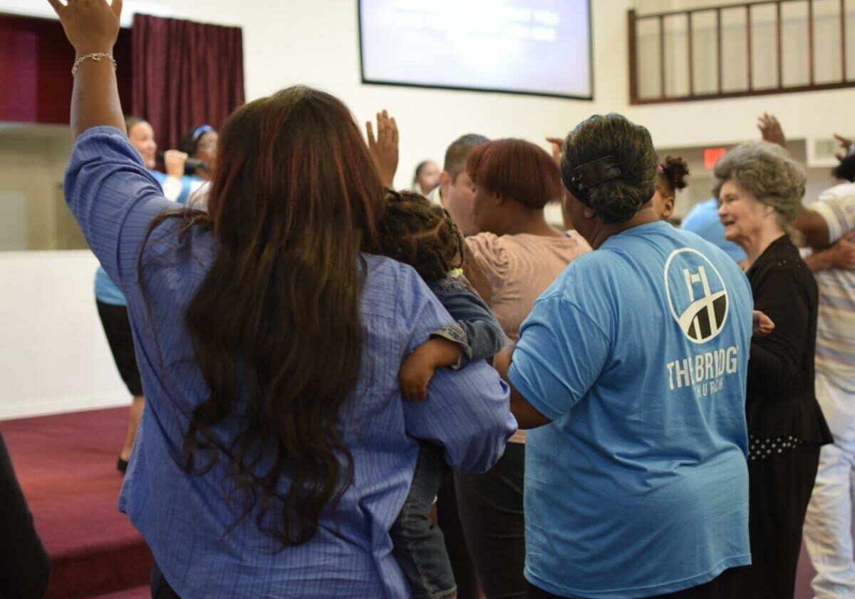 family is worshiping at the altar with arms raised holding a child